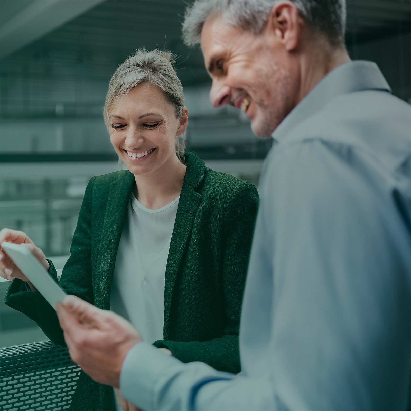 Businessman and businesswoman sharing digital tablet in factory.